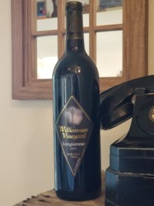 Dark bottle of 2021 Williamson Vineyards with vintage phone to the side and mirror on the wall behind the wine